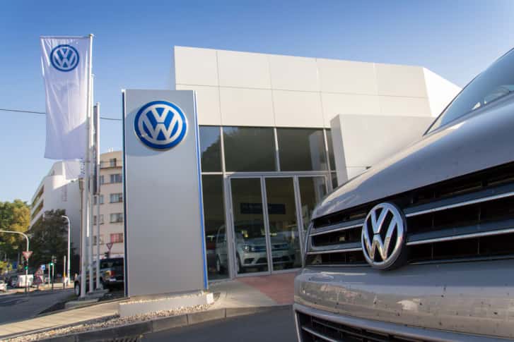 Car with Volkswagen logo in front of dealership building