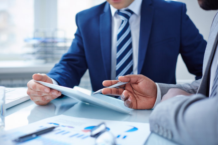 Image of two businessmen discussing computer project